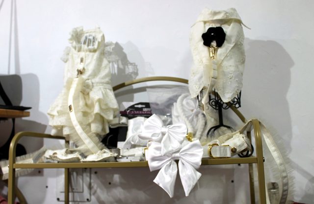 Vestidos y lazos blancos de ceremonia para perro colgados en el expositor de la boutique